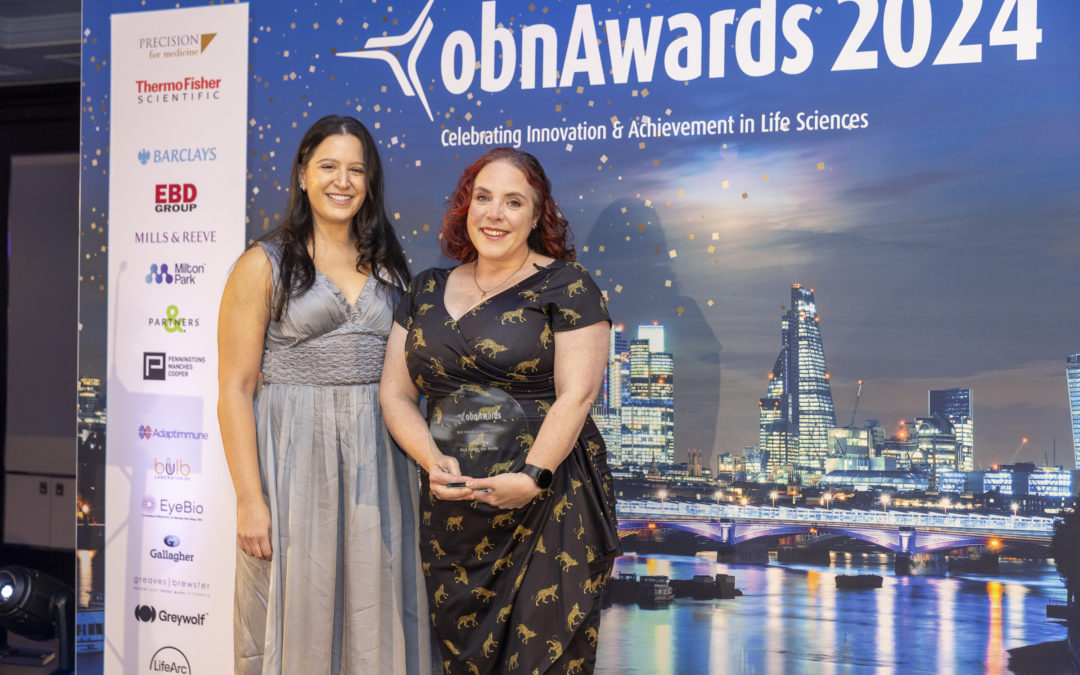 Two women standing in front of a background saying OBN Awards 2024, one of them holding an award and looking very happy